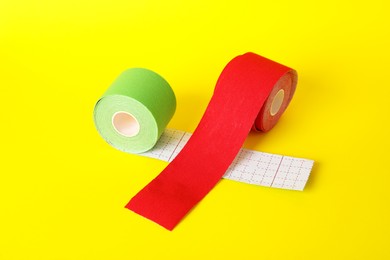 Photo of Bright kinesio tape in rolls on yellow background