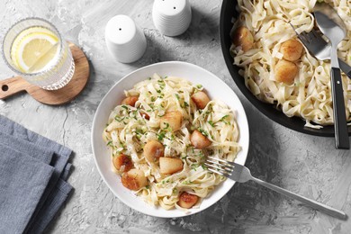 Photo of Delicious scallop pasta with spices served on gray textured table, flat lay