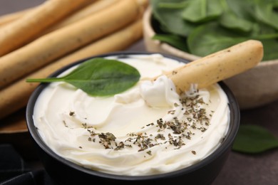 Delicious cream cheese with grissini stick and spices on table, closeup