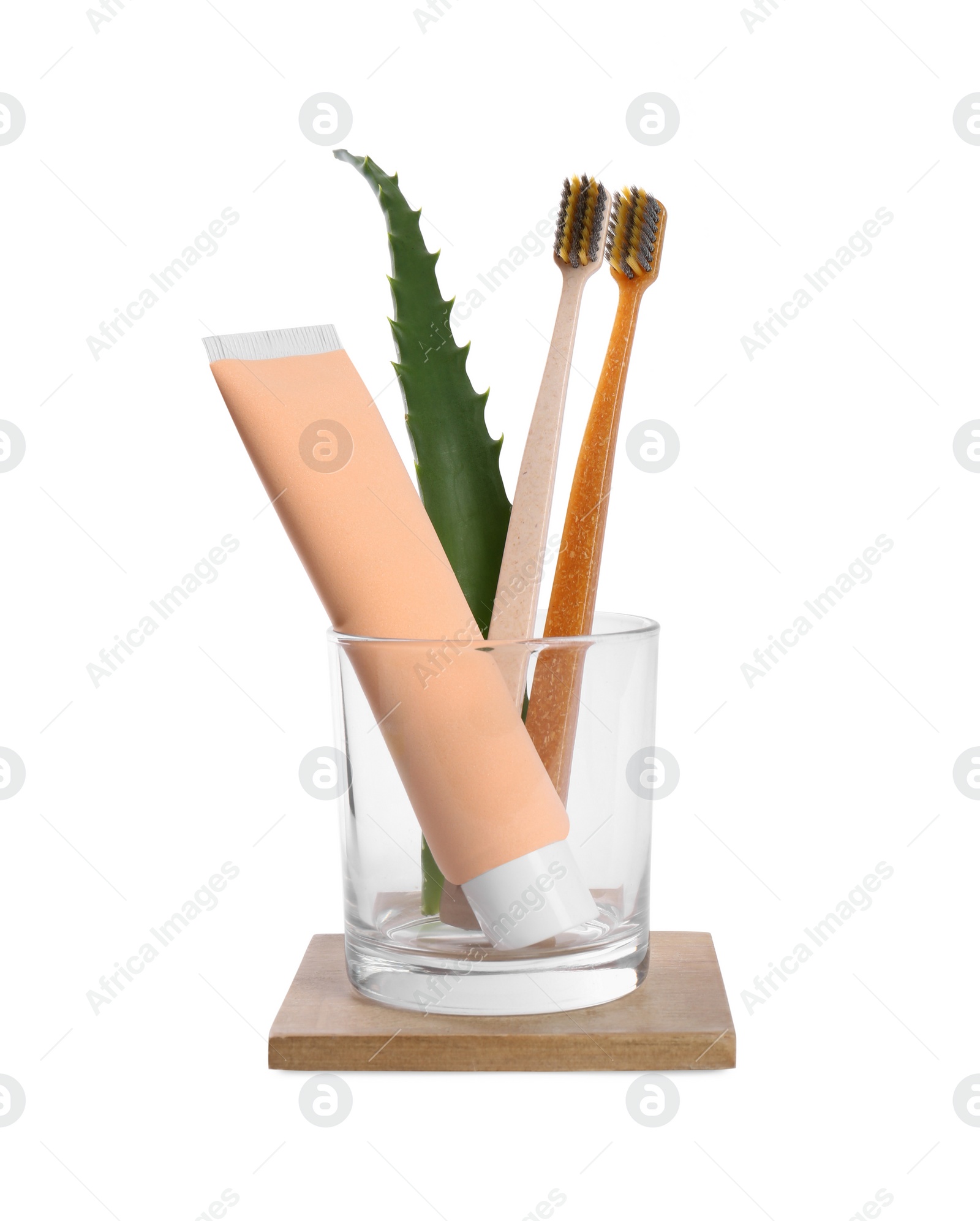 Photo of Tube of toothpaste, brushes and aloe vera leaf in glass on white background