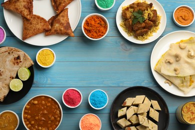 Photo of Frame of traditional Indian food and color powders on light blue wooden table, flat lay with space for text. Holi festival celebration