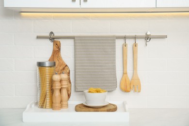 Photo of Clean towel, utensils and uncooked pasta in kitchen