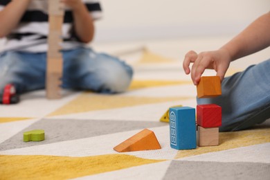 Little children playing with building blocks indoors, closeup. Wooden toys