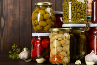 Jars of pickled vegetables on wooden table