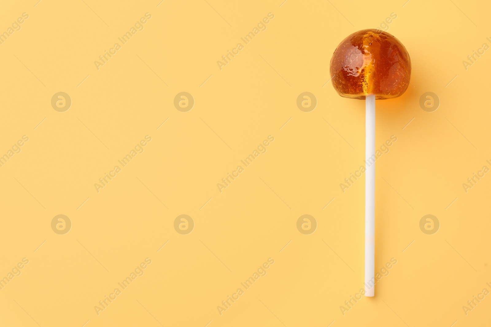 Photo of Tasty lollipop on yellow background, top view. Space for text