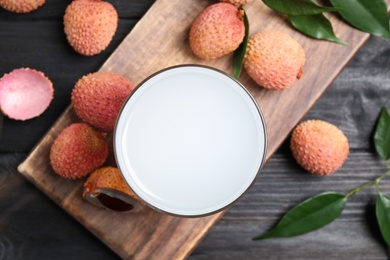 Photo of Fresh lychee juice and fruits on black wooden table, flat lay