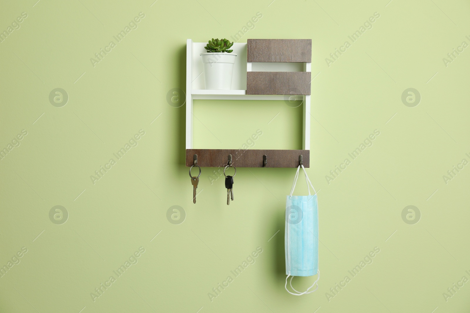 Photo of Wooden hanger for keys on light green wall