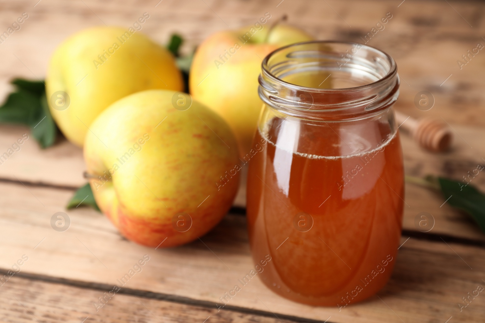 Photo of Jar of honey and apples on wooden table