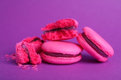 Photo of Delicious pink macarons on purple background, closeup