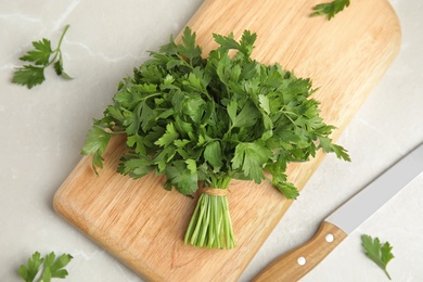 Photo of Board with fresh green parsley and knife on light background, top view