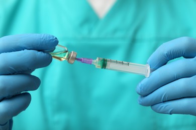 Doctor filling syringe with hepatitis vaccine from glass vial, closeup