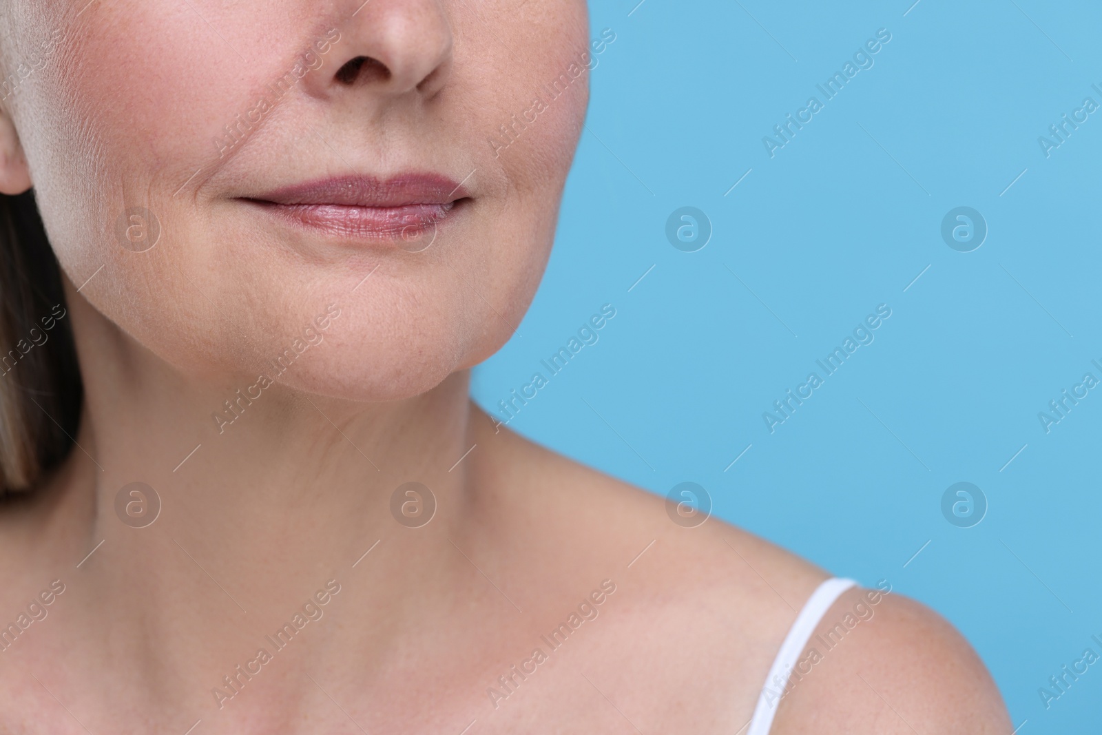 Photo of Senior woman with aging skin on light blue background, closeup. Rejuvenation treatment