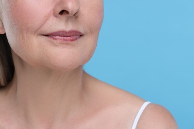 Photo of Senior woman with aging skin on light blue background, closeup. Rejuvenation treatment