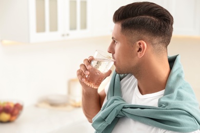Man drinking pure water from glass in kitchen. Space for text