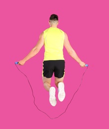 Sportive man training with jump rope on color background