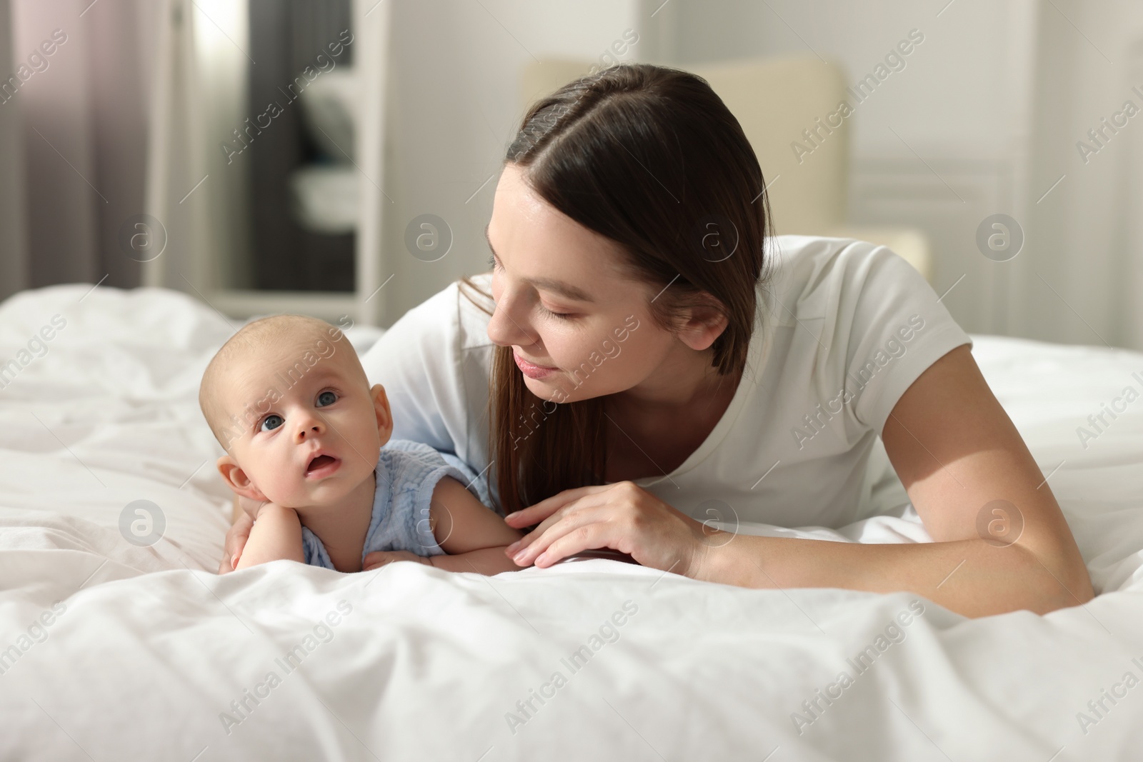 Photo of Mother with her cute baby on bed indoors