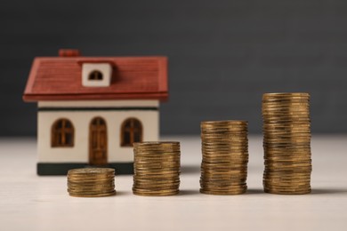 Photo of Mortgage. Stacked coins and house model on light table