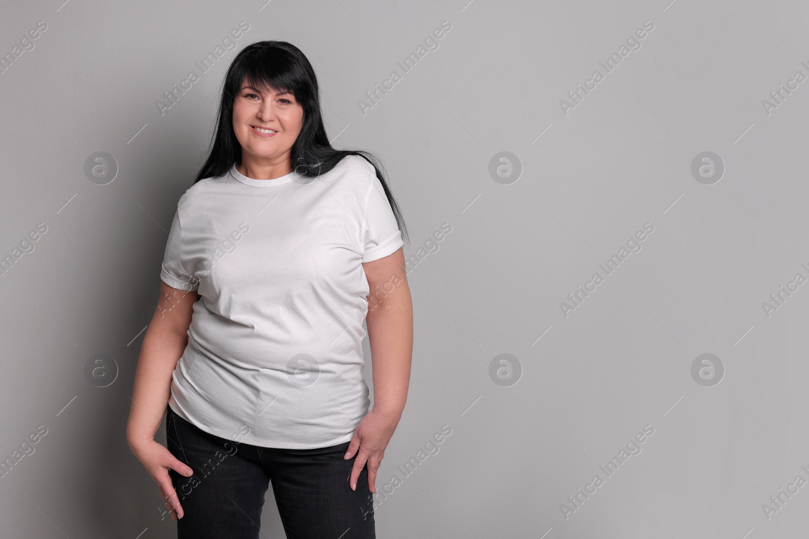 Photo of Beautiful overweight mature woman with charming smile on light grey background. Space for text
