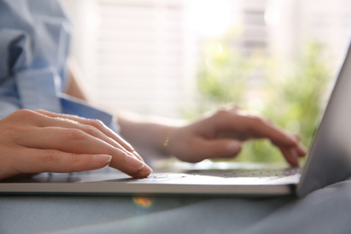 Photo of Woman working with modern laptop indoors, closeup