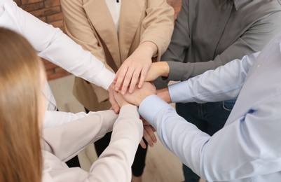 Photo of Group of people holding their hands together indoors, closeup