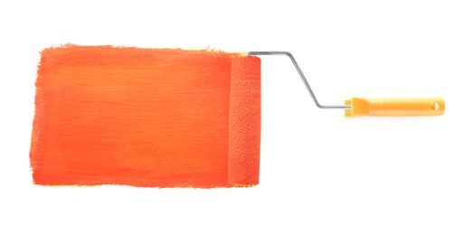 Photo of Applying coral paint with roller brush on white background, top view