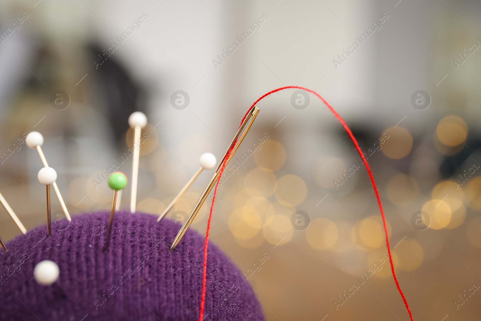 Photo of Cushion with pins on blurred background, closeup. Tailoring accessories