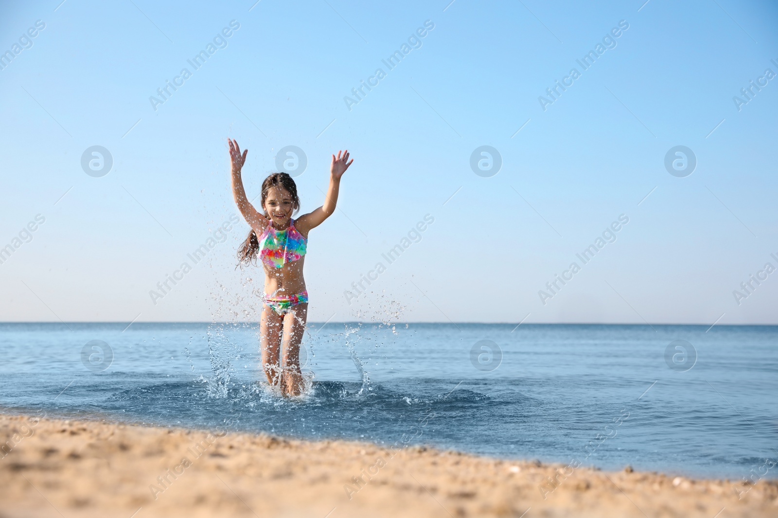 Photo of Cute little child having fun in sea on sunny day. Beach holiday