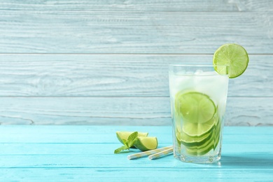 Photo of Natural lemonade with lime in glass on wooden table