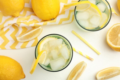 Photo of Soda water with lemon slices and ice cubes on white table, flat lay