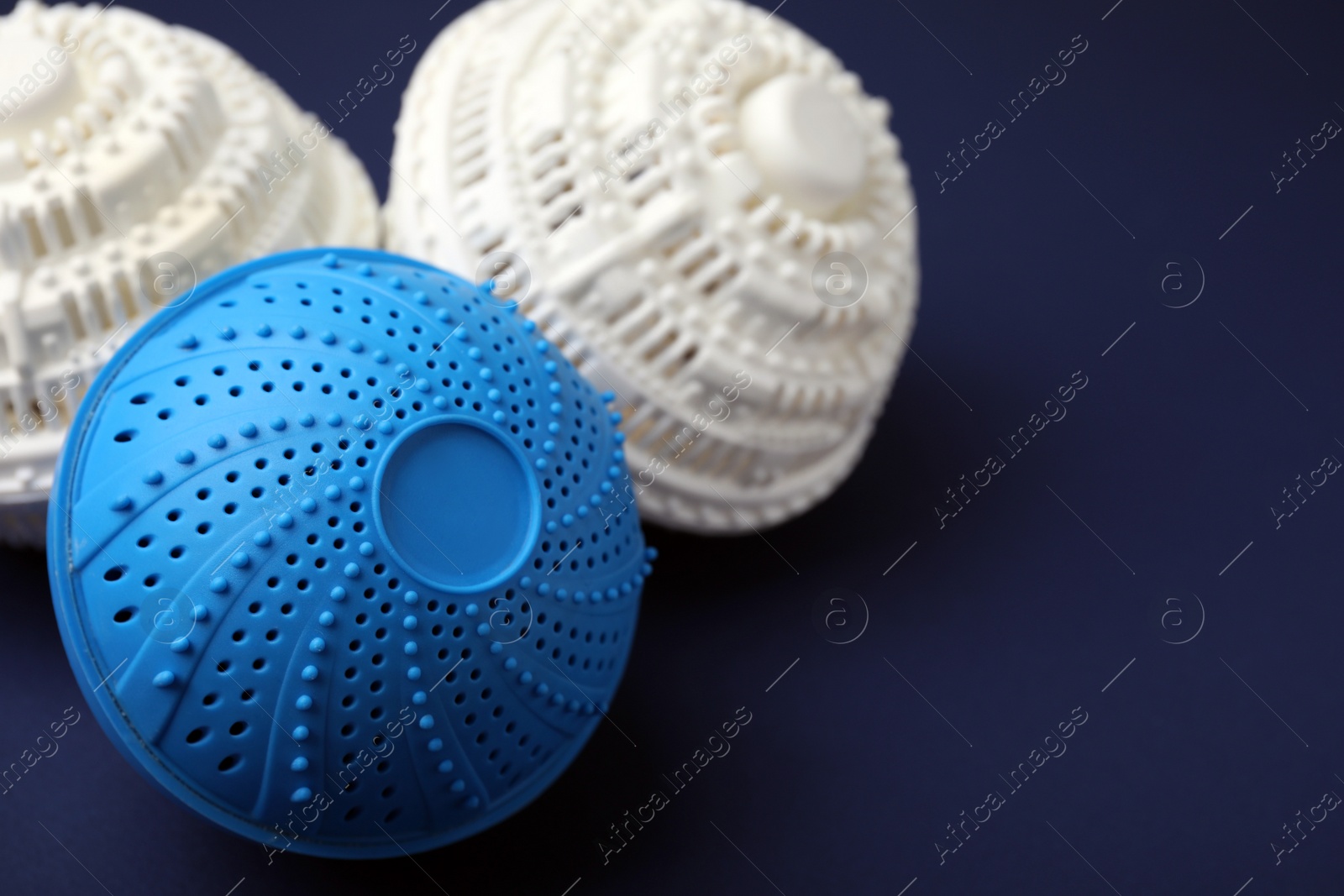 Photo of Laundry dryer balls on dark blue background, closeup. Space for text