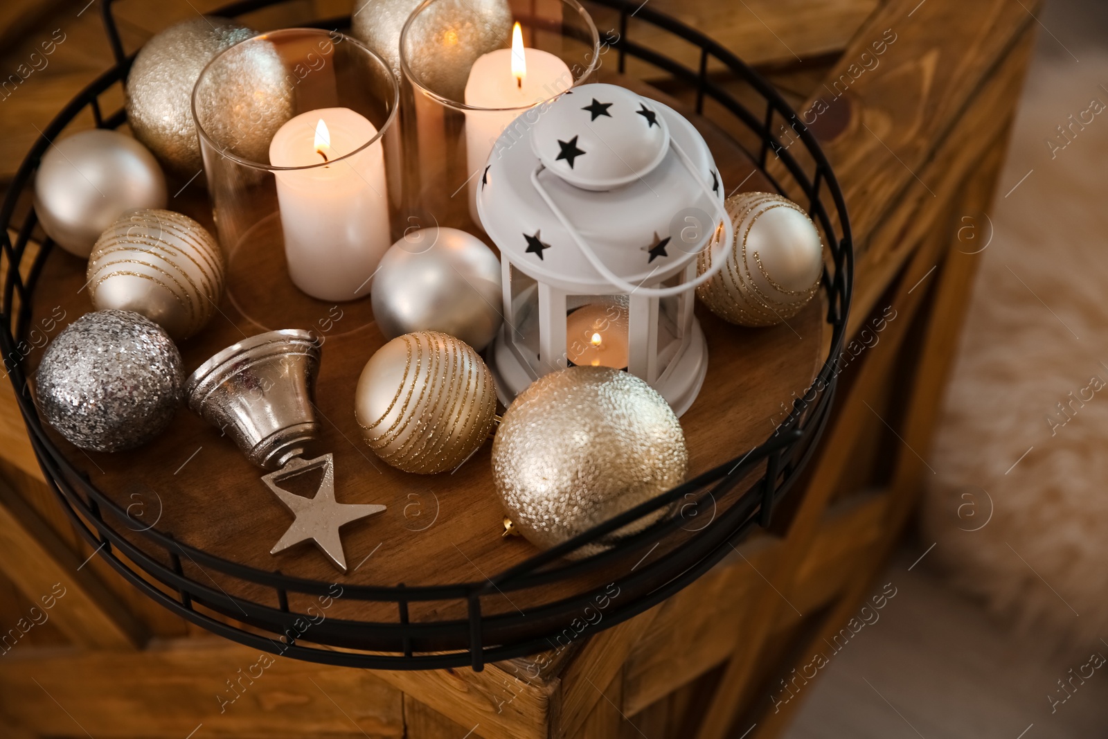 Photo of Burning candles, lantern and Christmas balls on wooden box indoors, above view