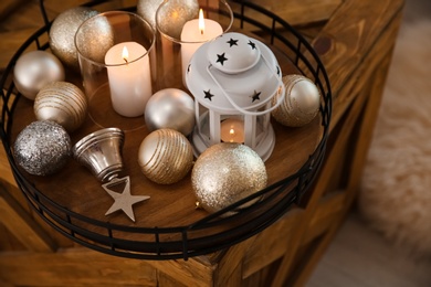 Burning candles, lantern and Christmas balls on wooden box indoors, above view