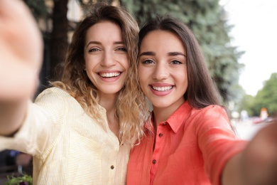 Beautiful young women taking selfie outdoors on sunny day