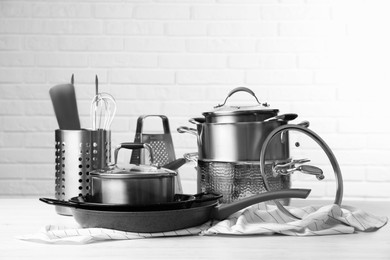 Photo of Set of clean kitchenware on white table against brick wall