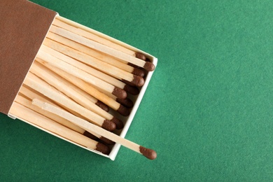 Photo of Open box with matches on color background, top view. Space for text