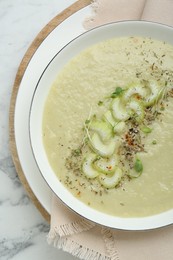 Bowl of delicious celery soup on white table, top view