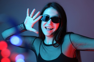 Photo of Portrait of beautiful young woman with sunglasses on color background