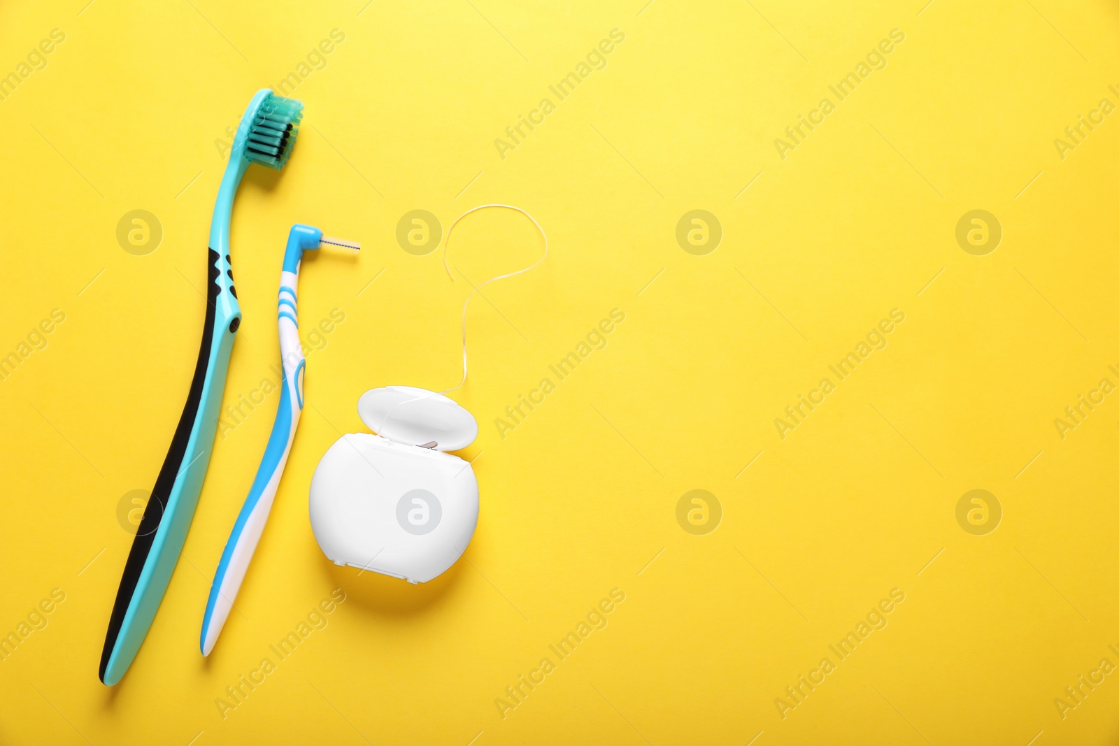 Photo of Flat lay composition with dental floss and different teeth care products on yellow background. Space for text