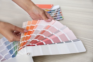 Photo of Female interior designer with color palette samples at wooden table, closeup