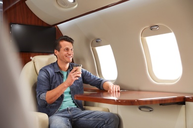 Handsome man with paper cup on plane. Air travel