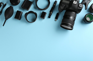 Flat lay composition with camera and video production equipment on light blue background, space for text