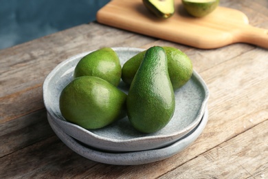 Plate with ripe avocados on wooden table