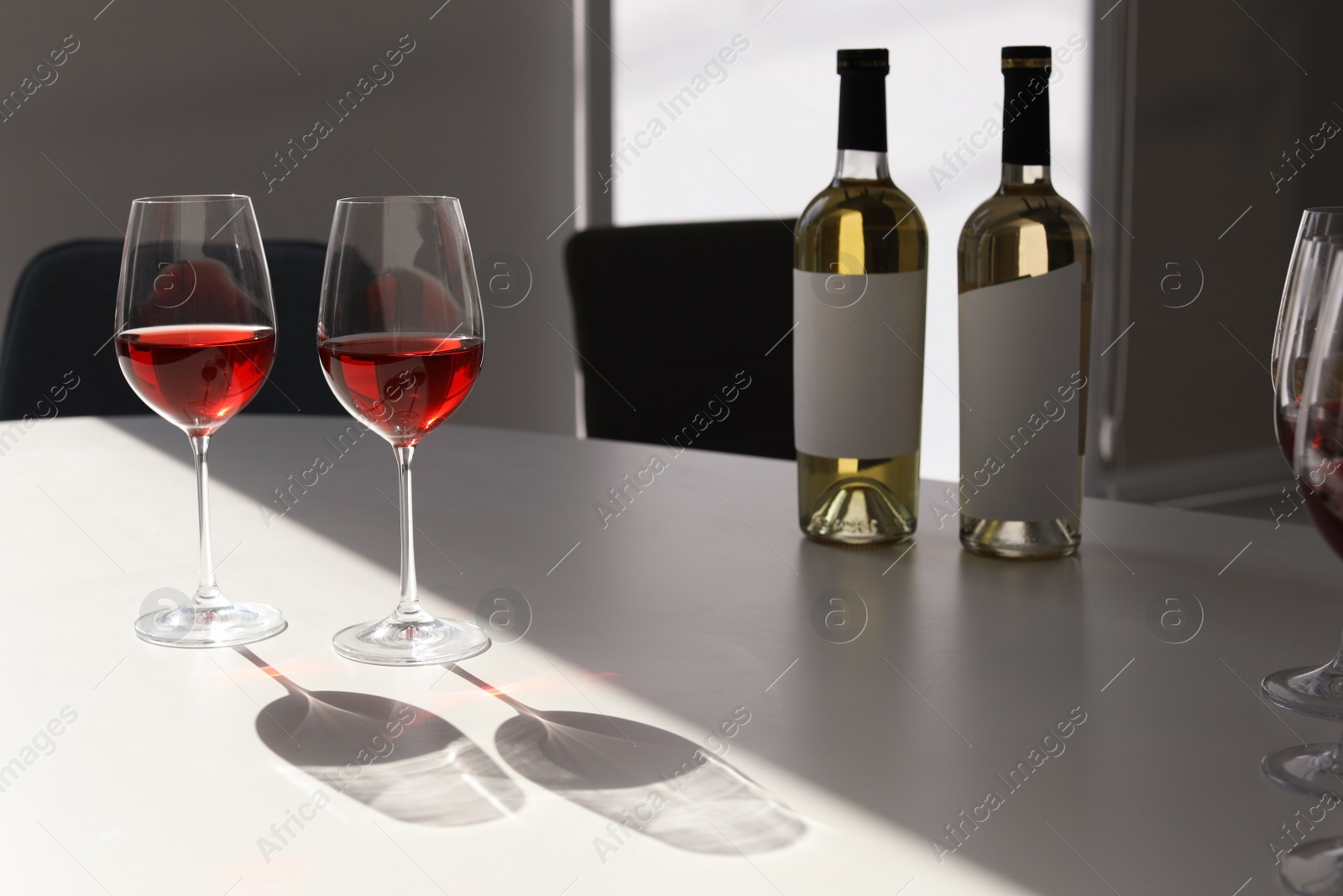 Photo of Glasses and bottles with delicious wine on table indoors