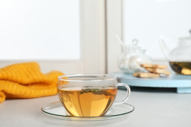 Photo of Cup of fresh tea on windowsill indoors. Winter drink