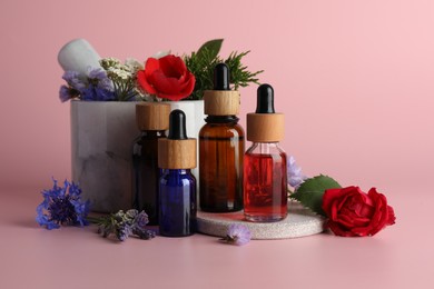 Aromatherapy. Different essential oils, flowers, mortar and pestle on pink background