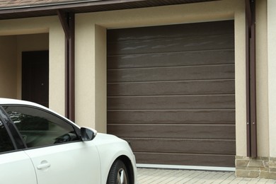 Building with brown sectional garage door and parked car