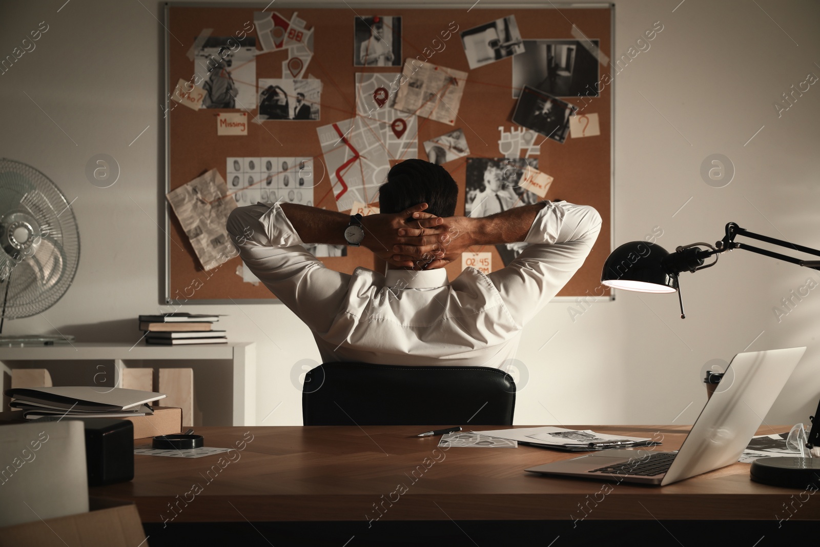 Photo of Detective looking at evidence board in office, back view