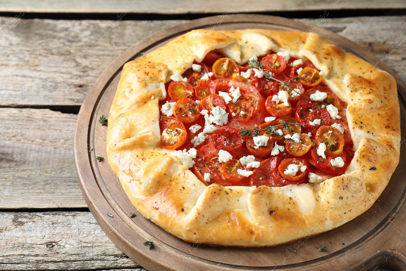 Photo of Tasty galette with tomato, thyme and cheese (Caprese galette) on wooden table, closeup