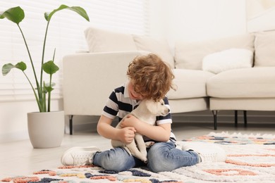 Photo of Little boy hugging cute puppy on carpet at home