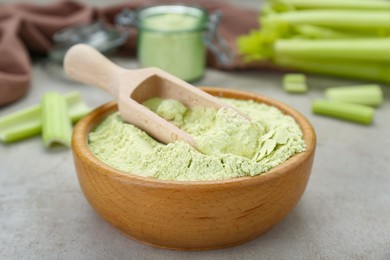 Photo of Wooden bowl and scoop with natural celery powder on grey table, closeup